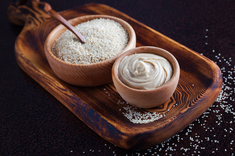 bowl with sesame seeds and tahini on a wooden board
